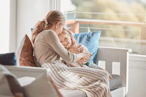Mère et sa fille blotties l'une contre l'autre sur un canapé