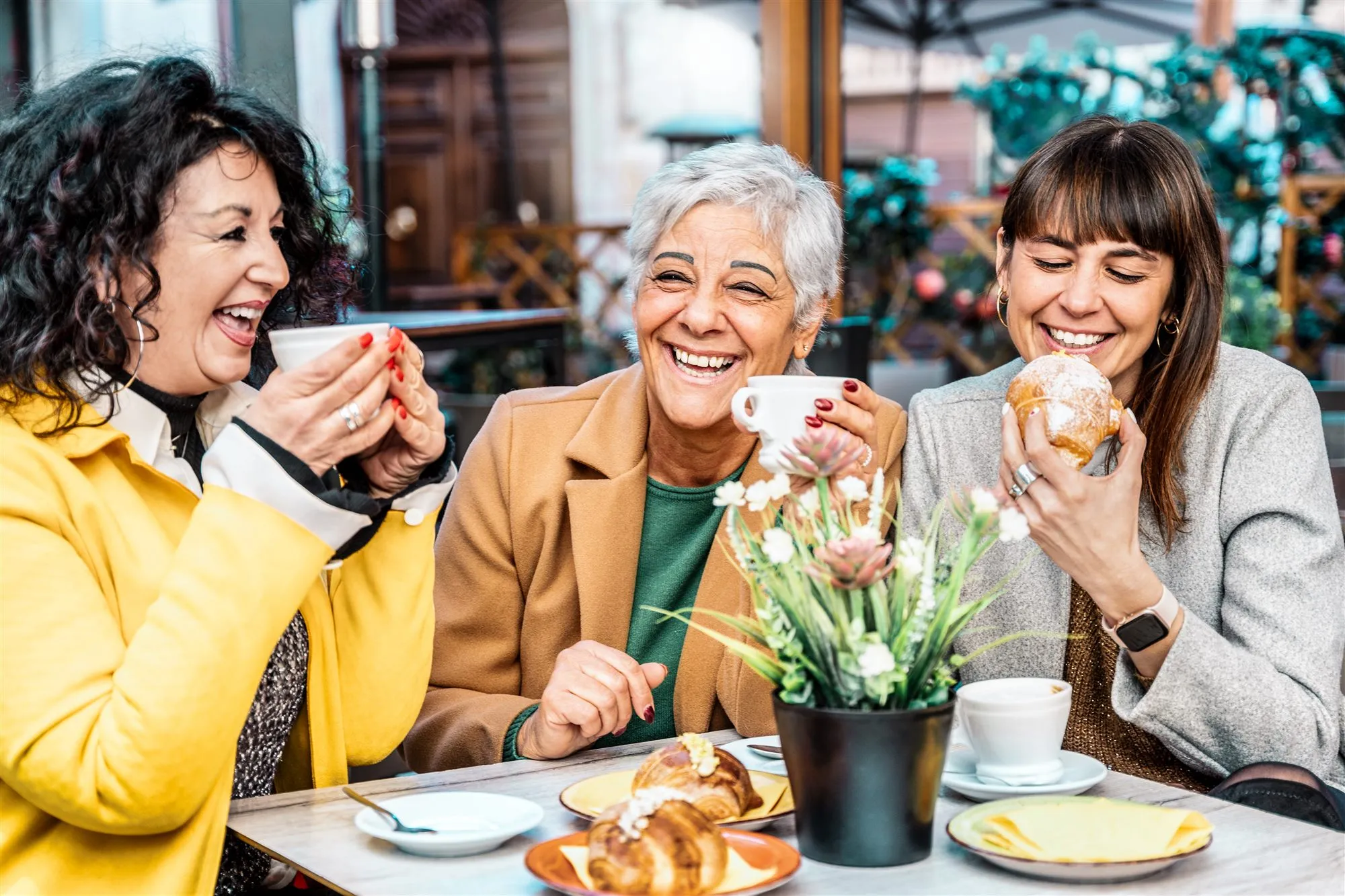 Trois femmes d'âges différents qui rient autour d'un café