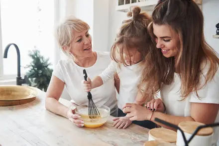 Grand-mère, mère et petite fille qui cuisinent ensemble dans une cuisine claire