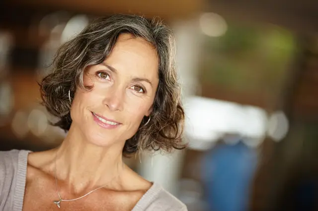 Femme d'une cinquantaine d'années aux cheveux grisonnants, au sourire serein